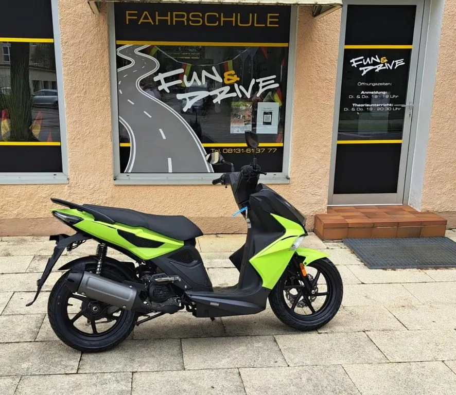 Grüner Roller vor dem Schaufenster der Fahrschule Fun & Drive