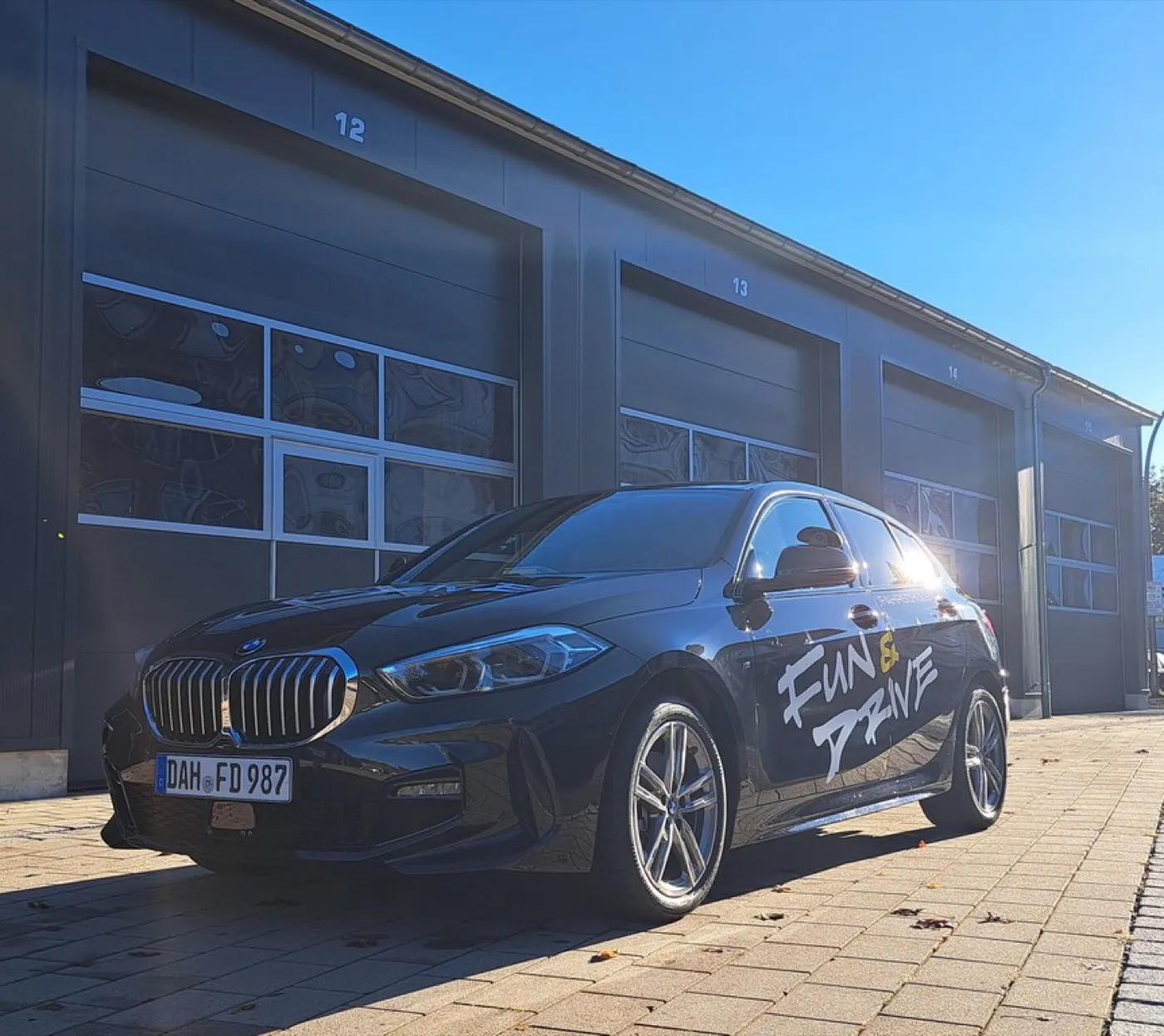 Schwarzer BMW 1er der Fahrschule Fun & Drive mit Fun-&-Drive-Schriftzug an der Fahrzeugseite